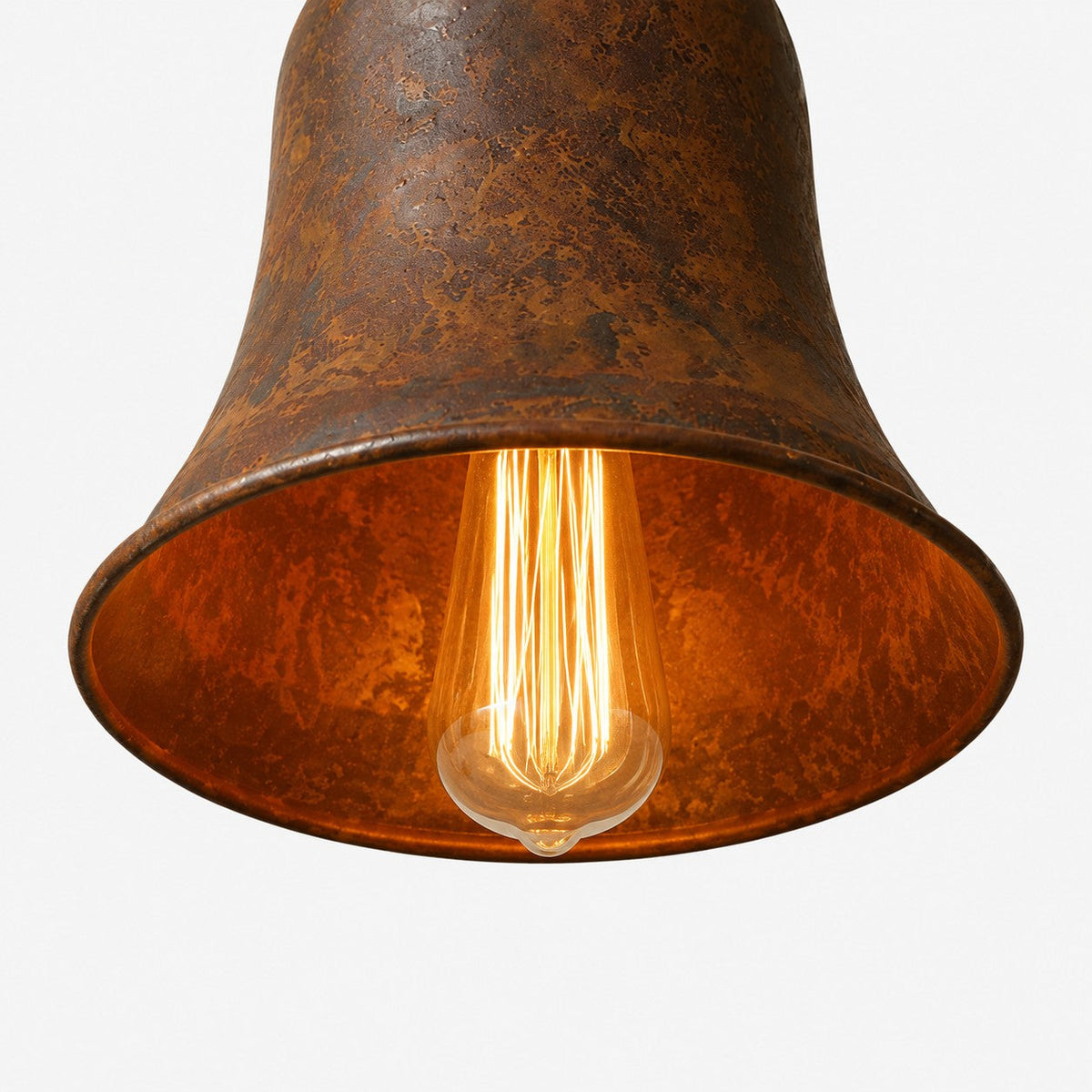 Warm bulb glow below rust metal pendant shade