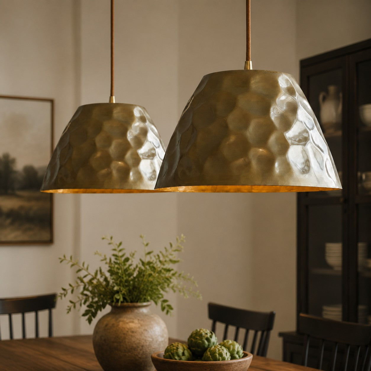 Pair of hammered brass pendant lights above a dining table