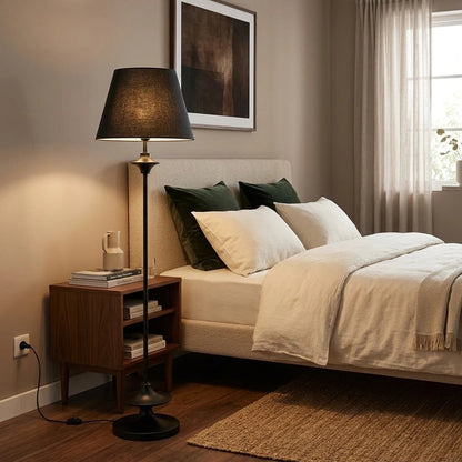 Black floor lamp beside a bedroom nightstand