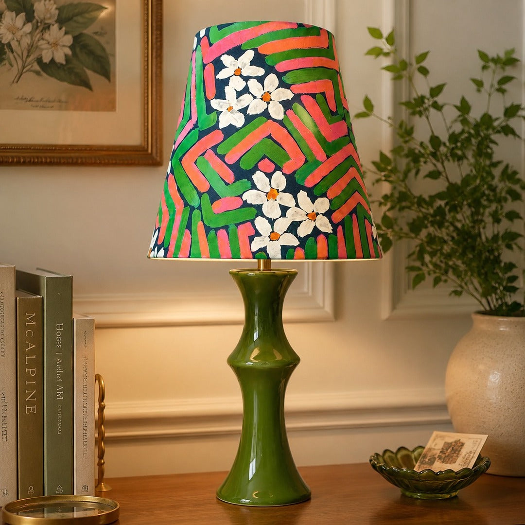 Pink and green table lamp glowing beside framed wall art