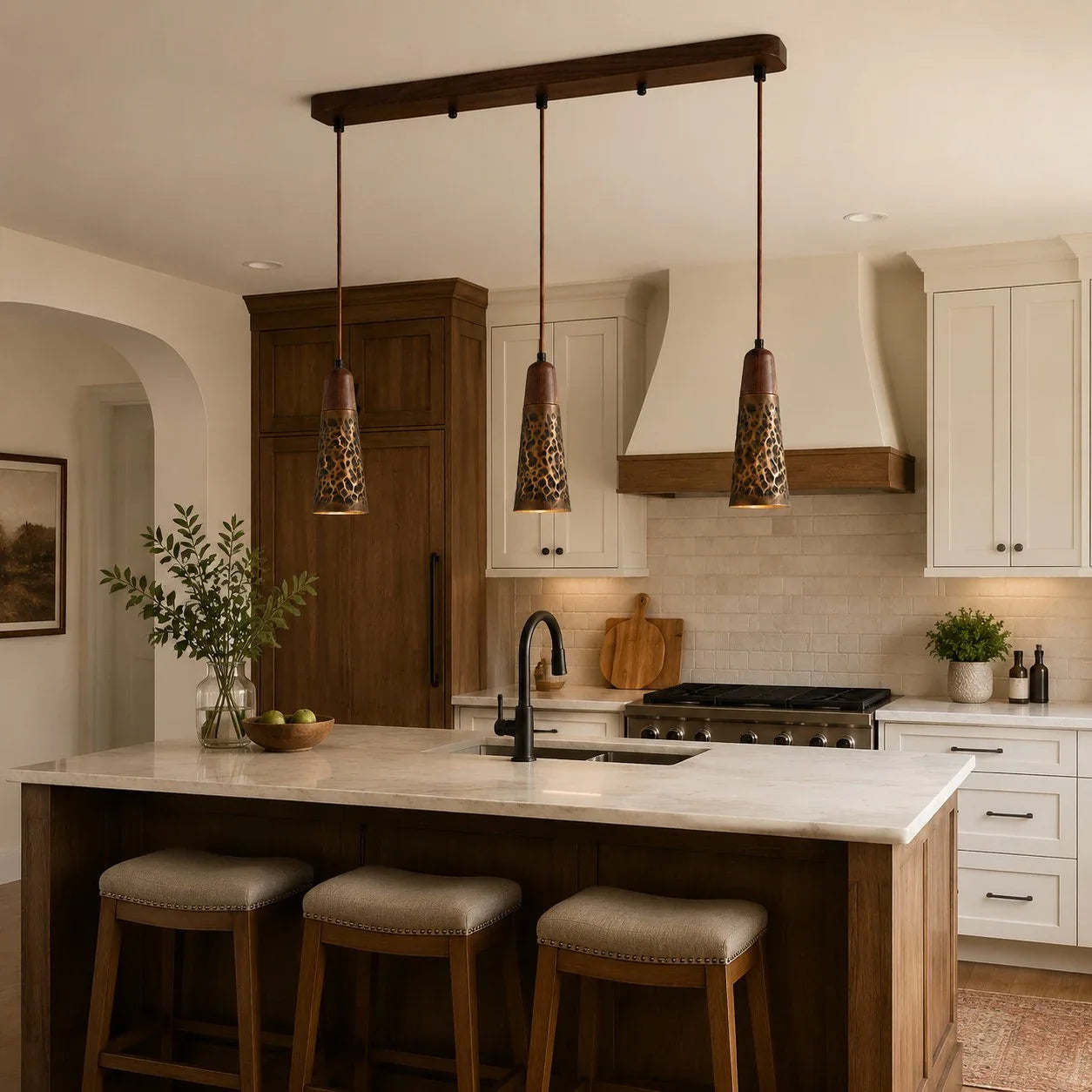 Three hammered copper pendant lights above a kitchen island