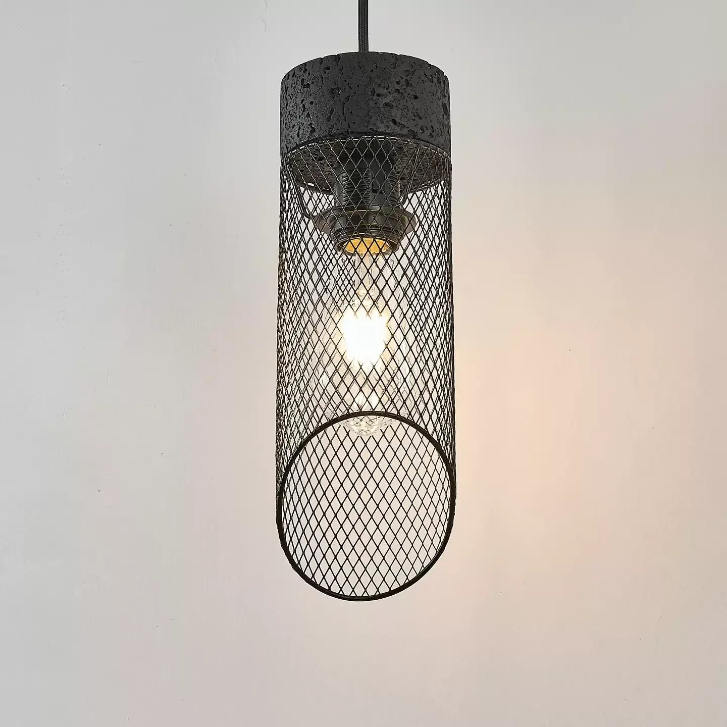 Black mesh pendant shade lit with a visible bulb inside