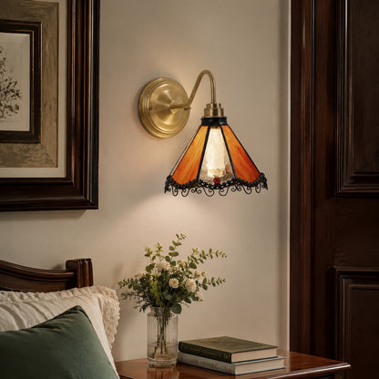 Orange stained glass wall sconce beside a vanity mirror