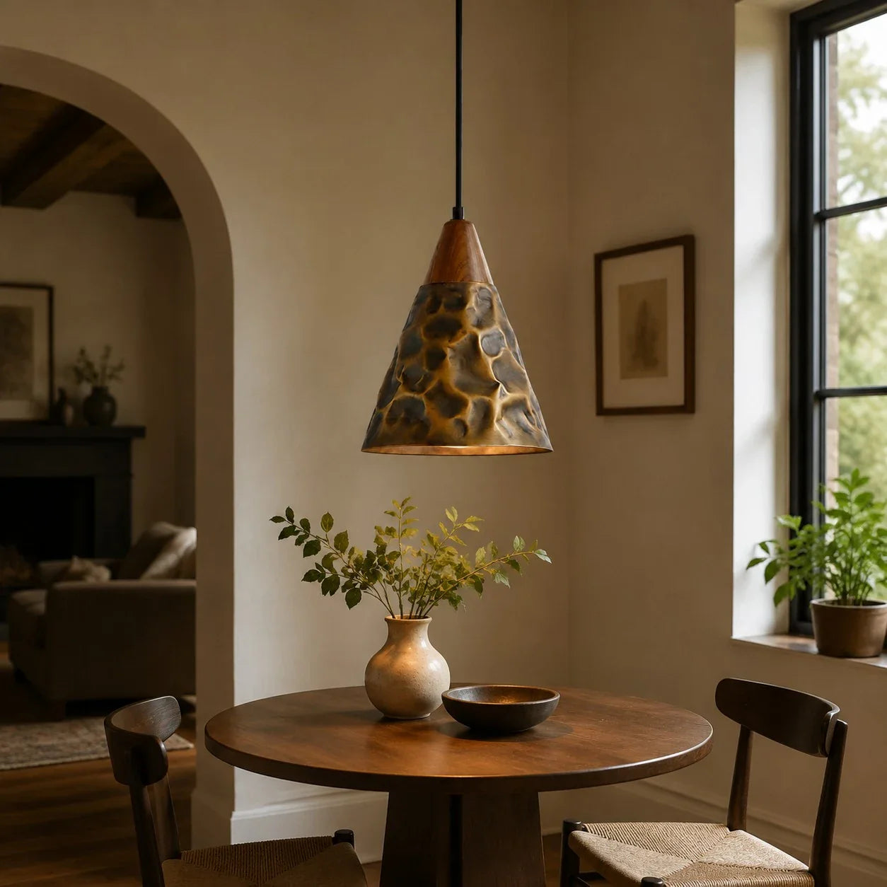 Single hammered copper pendant beside a dining table