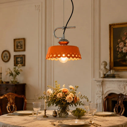 Orange metal and ceramic pendant lamp glowing over a classic dining setting