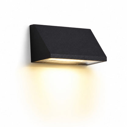 Black wall light glowing on an exterior wall at night