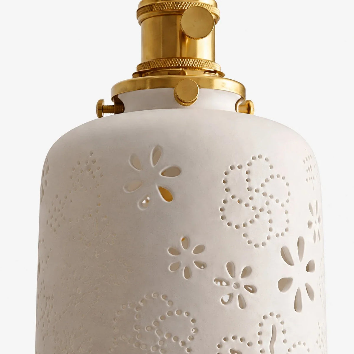 Close view of white ceramic shade with cutout floral pattern
