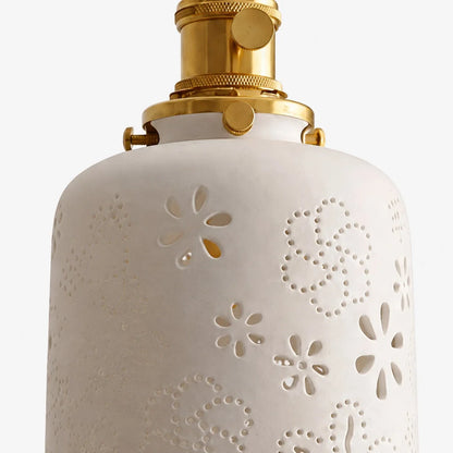 Close view of white ceramic shade with cutout floral pattern