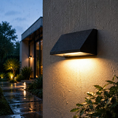 Black sloped outdoor wall light illuminated on a clean background