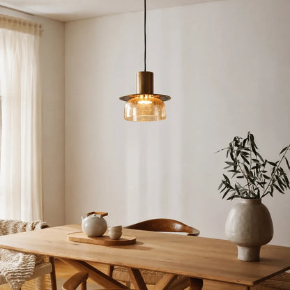 Amber brass glass pendant light above a wood dining table