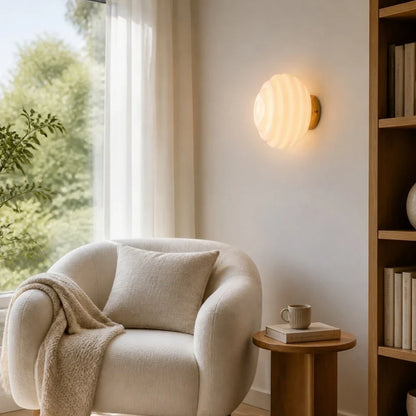 Cream ribbed glass wall lamp beside a lounge chair