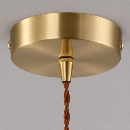 Warm lit glass shade detail on brass pendant light