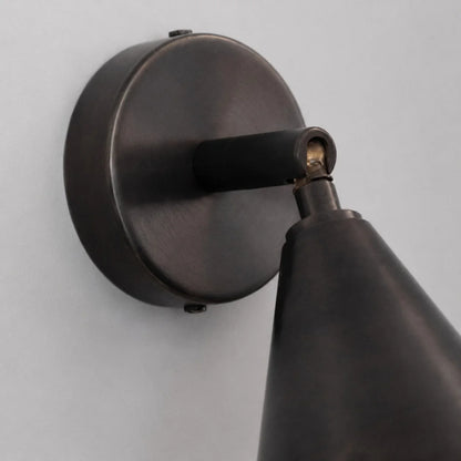 Round wall plate and adjustable arm detail on matte black wall light